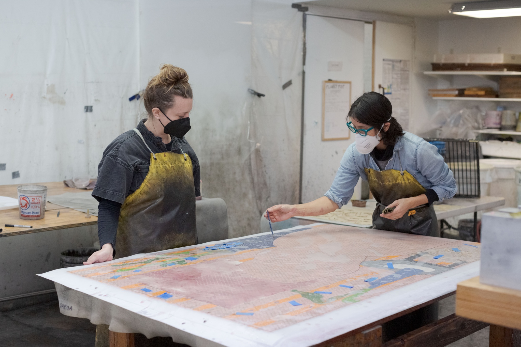 Blair Saxon-Hill and Akemi Martin pigmenting an oversized sheet of handmade paper.