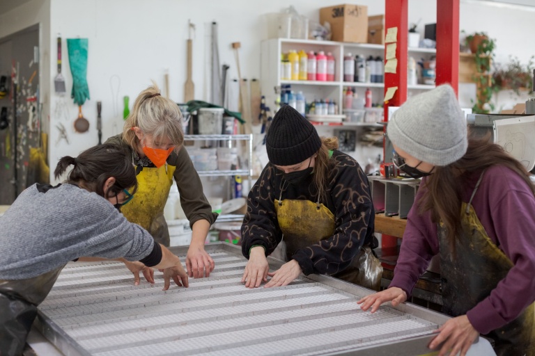 Papermakers Akemi Martin, Rachel Gladfelter and Emily Chaplain couche a sheet of handmade paper with Blair Saxon-Hill.